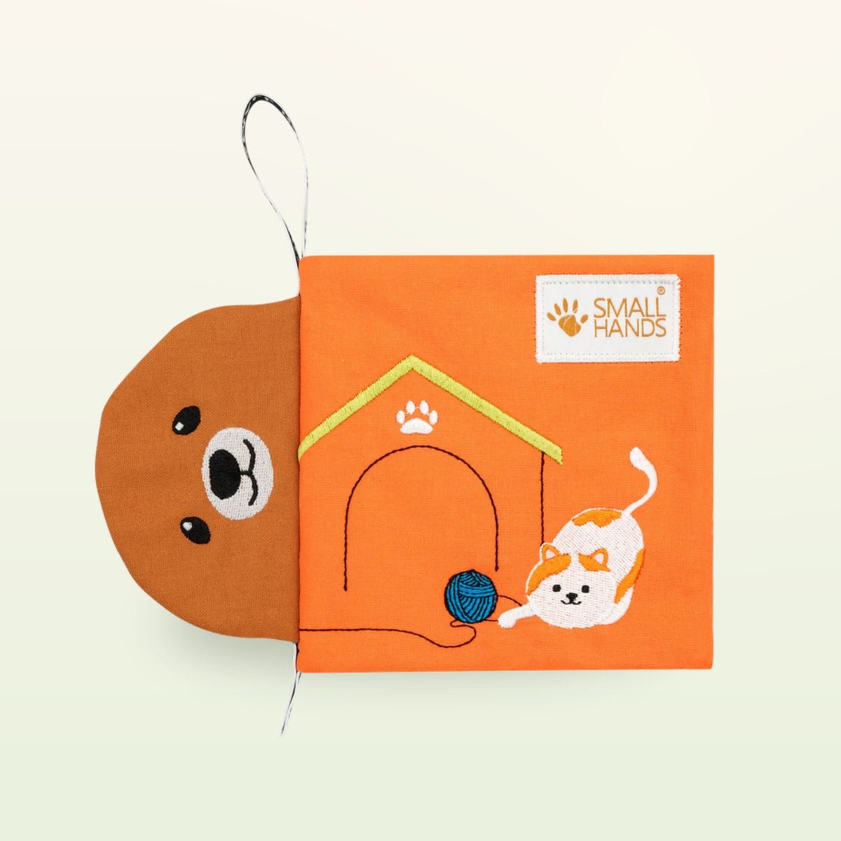 Small Hands Pets Montessori cloth book – orange cover with dog face, dog house and playing cat on a soft cream background – from 0 months