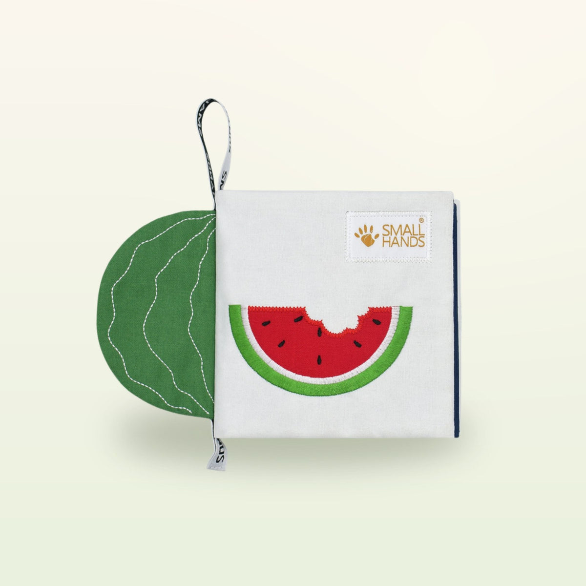 Small Hands Exotic Fruits Montessori cloth book – cover with bitten watermelon on a soft cream background – from 0 months