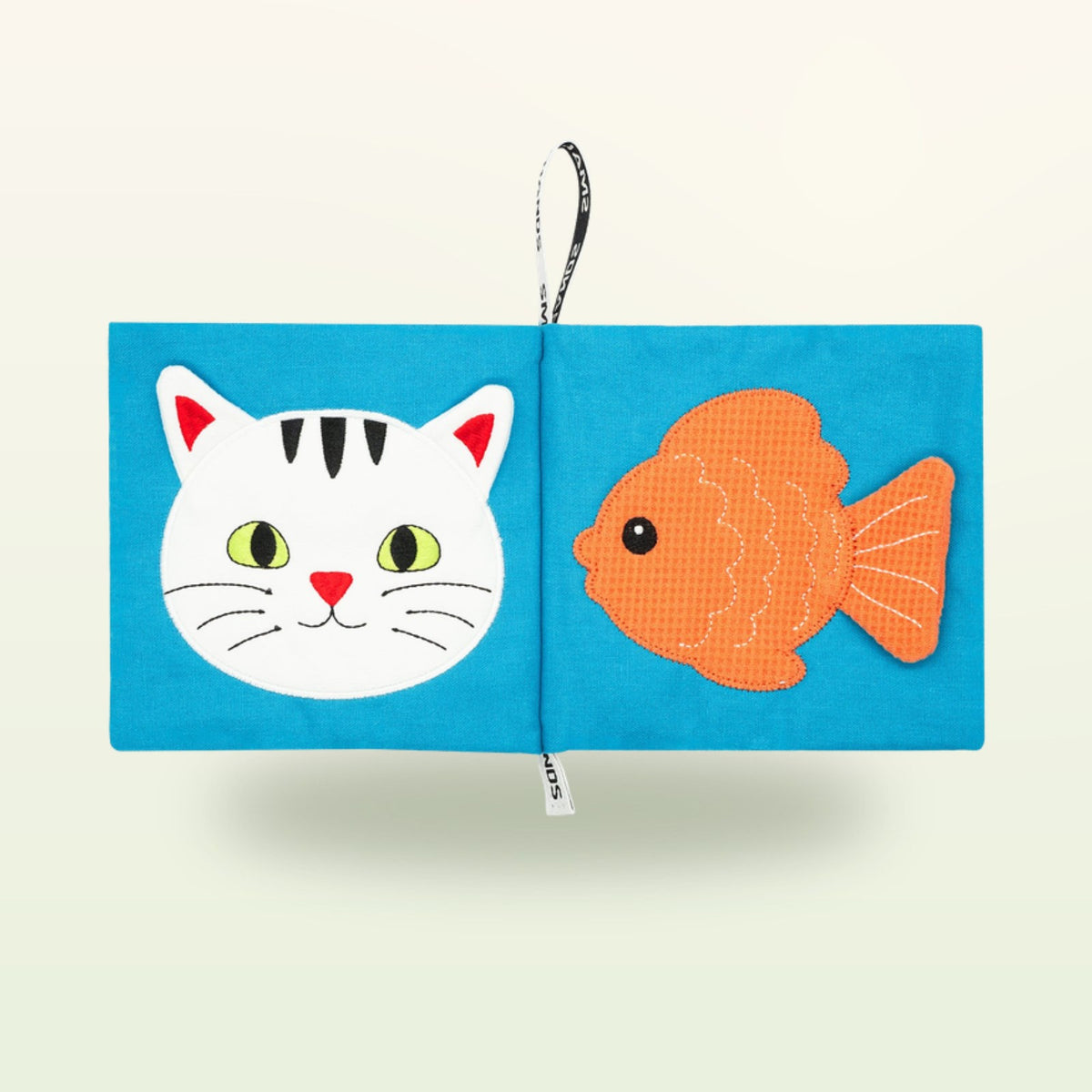 Small Hands Pets Montessori cloth book open – cat face and goldfish on a soft cream background – from 0 months