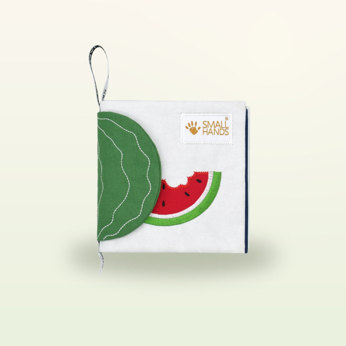 Small Hands Exotic Fruits Montessori cloth book closed with watermelon and leaf flap on a soft cream background – from 0 months