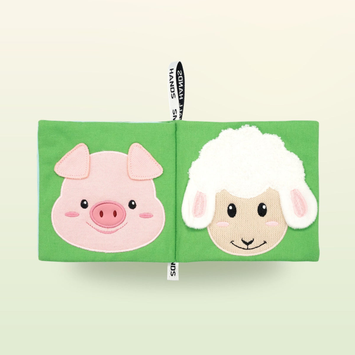 My First Book Small Hands Farm cloth book double page with pig and sheep on a soft meadow green background – from 0 months