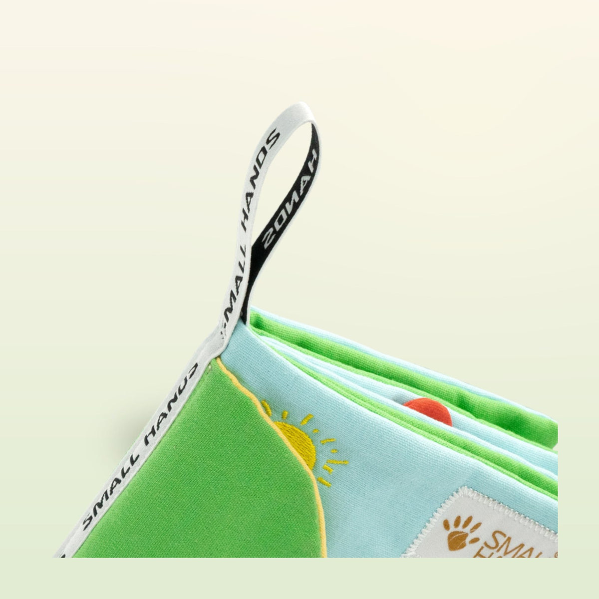My First Book Small Hands Farm cloth book open with hanging loop on a soft meadow green background – from 0 months