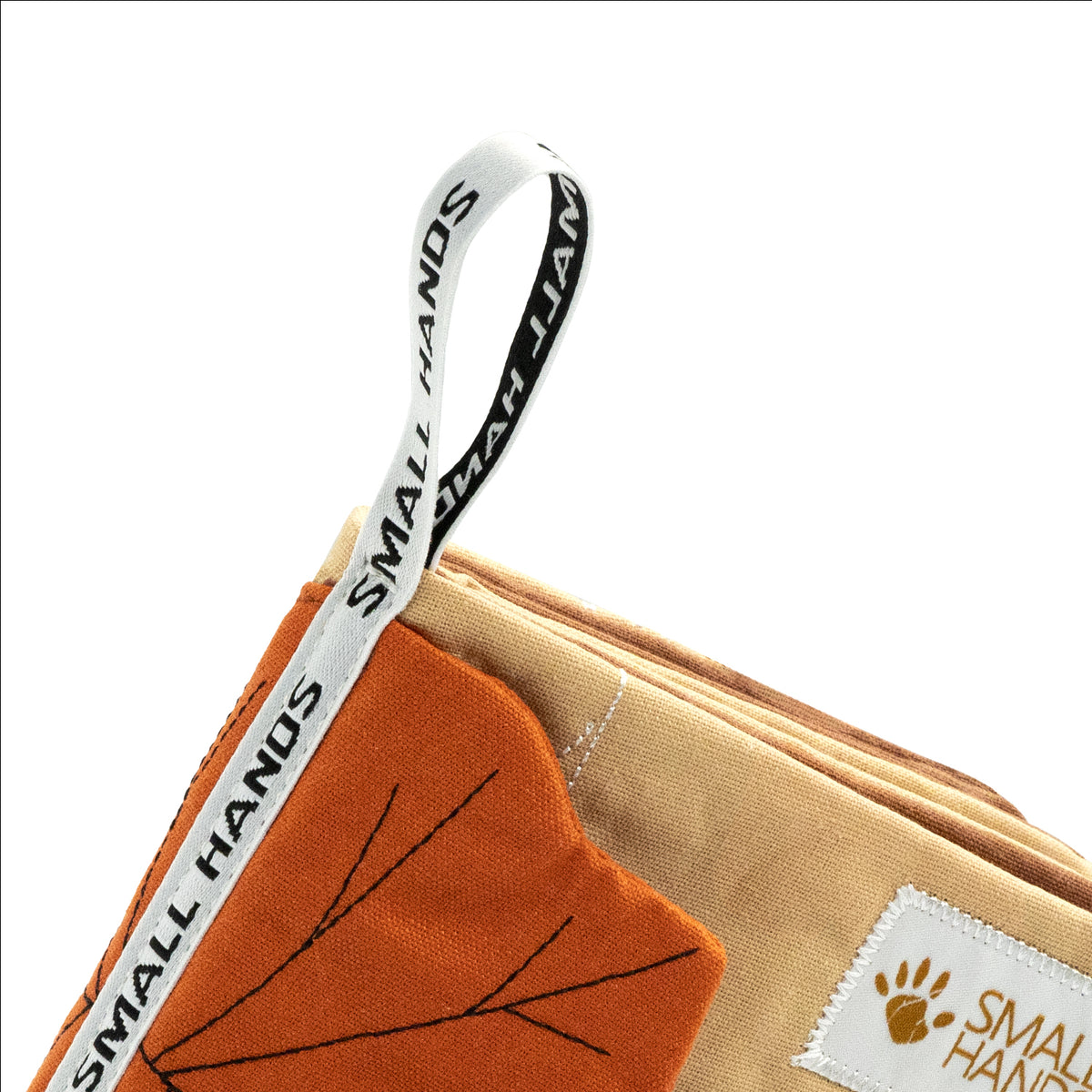 Small Hands Wild Animals cloth book: close-up of the woven grasping loop with Small Hands lettering, touchable maple leaf and soft fabric pages – baby book detail
