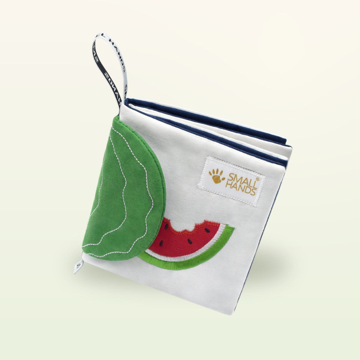 Small Hands Exotic Fruits Montessori cloth book from above with watermelon and leaf flap on a soft cream background – from 0 months