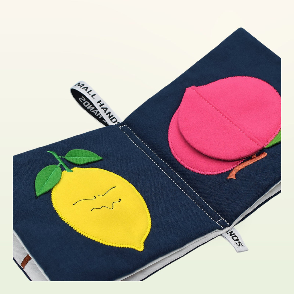 Small Hands Colorful Fruits Montessori cloth book open – yellow lemon and pink peach on a soft cream background – from 0 months