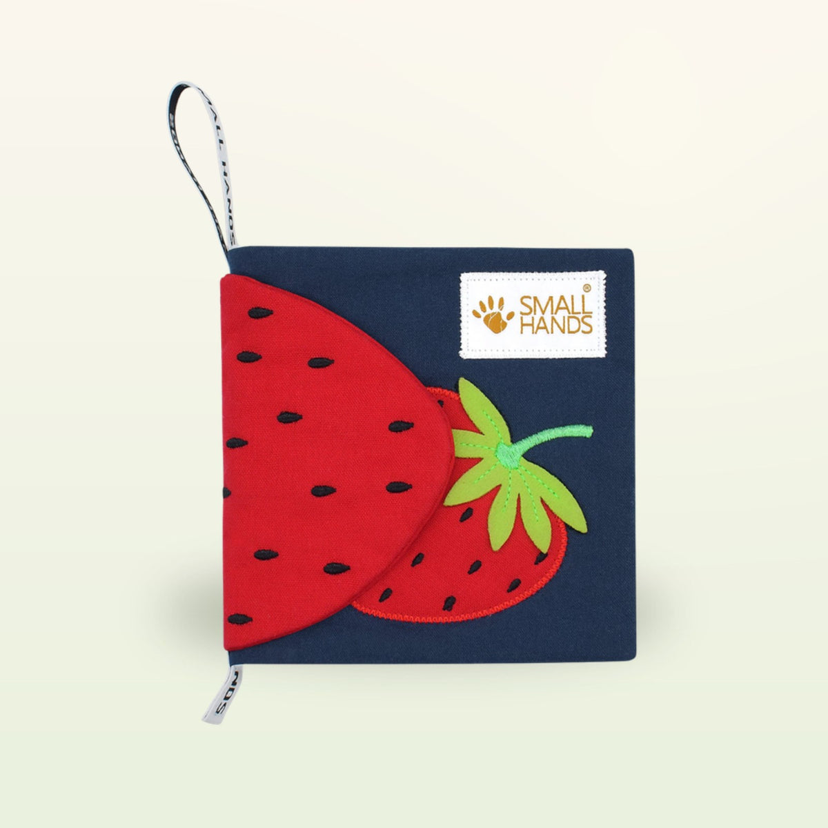 Small Hands Colorful Fruits Montessori cloth book – cover with red strawberry and Small Hands loop on a soft cream background – from 0 months