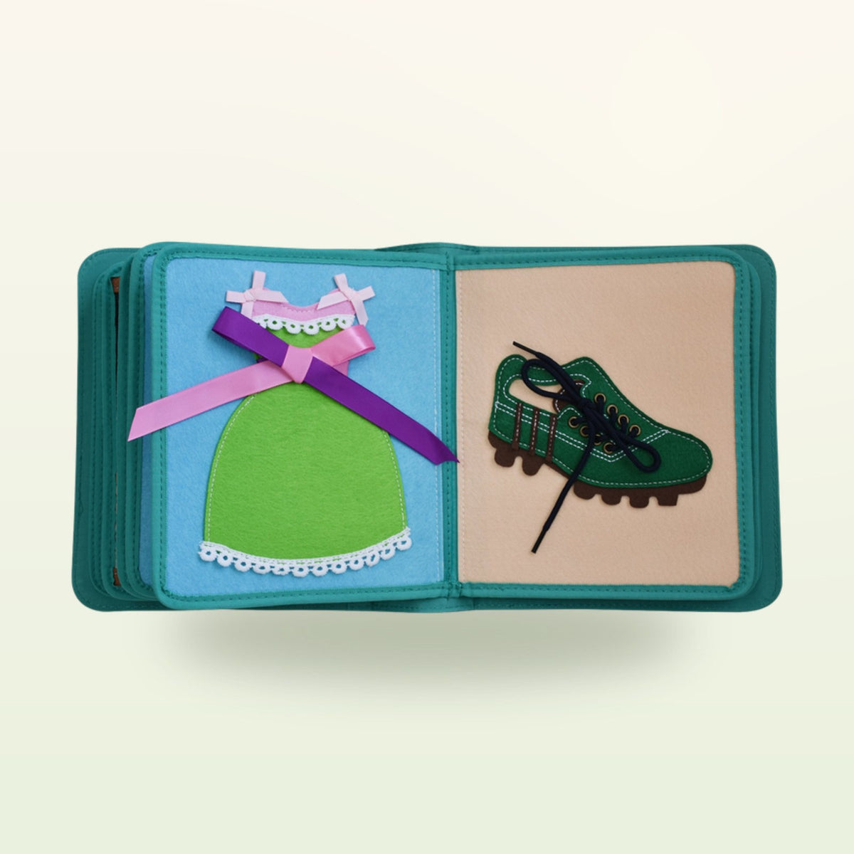 Dressing book fabric page with green dress with bow and green lace-up shoe on a soft cream background – from 3 years