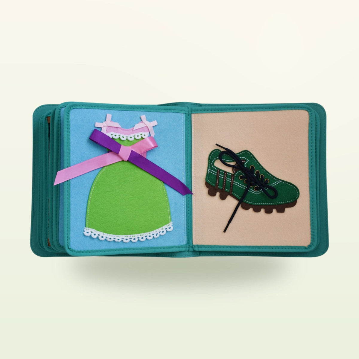 Dressing book fabric page with green dress with bow and green lace-up shoe on a soft cream background – from 3 years