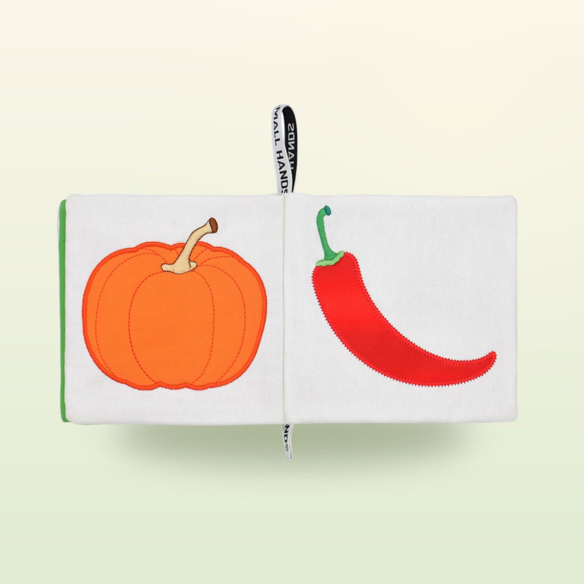 Small Hands Vegetables Montessori cloth book double page with pumpkin and chili pepper on a soft meadow green background – from 1 year