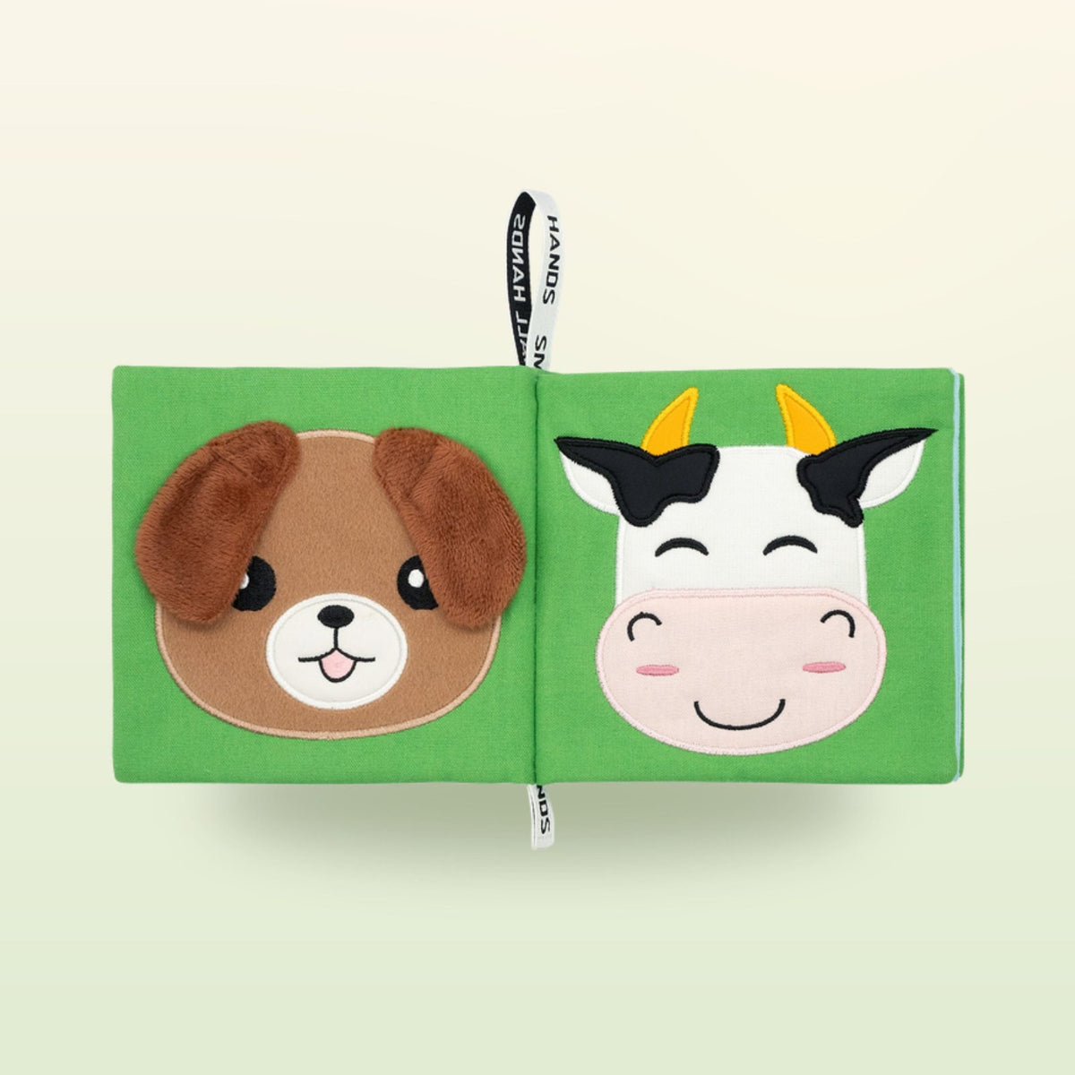 My First Book Small Hands Farm cloth book double page with dog and cow on a soft meadow green background – from 0 months