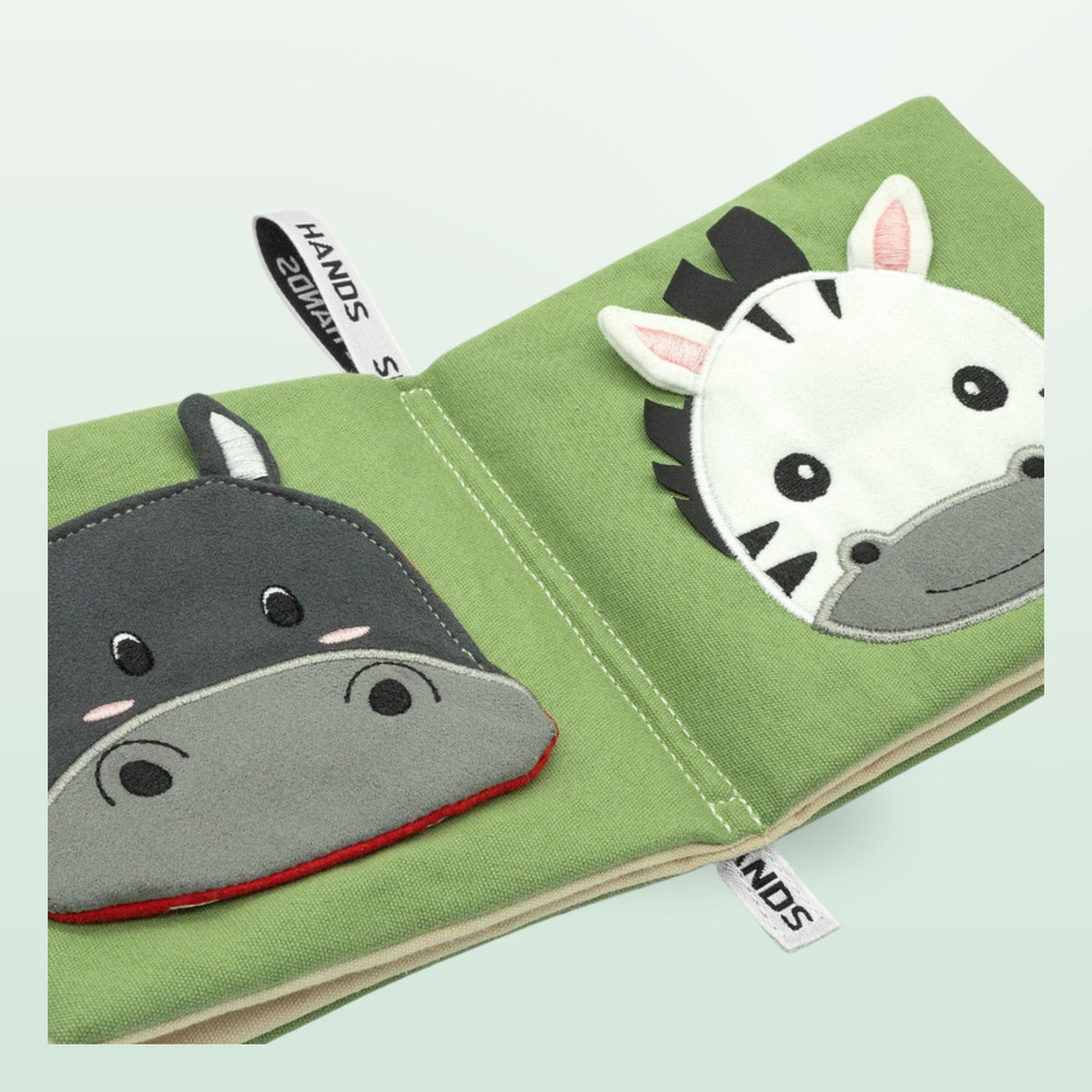 Small Hands Animals of Africa Montessori cloth book close-up with hippo and zebra on a soft forest green background – from 0 months
