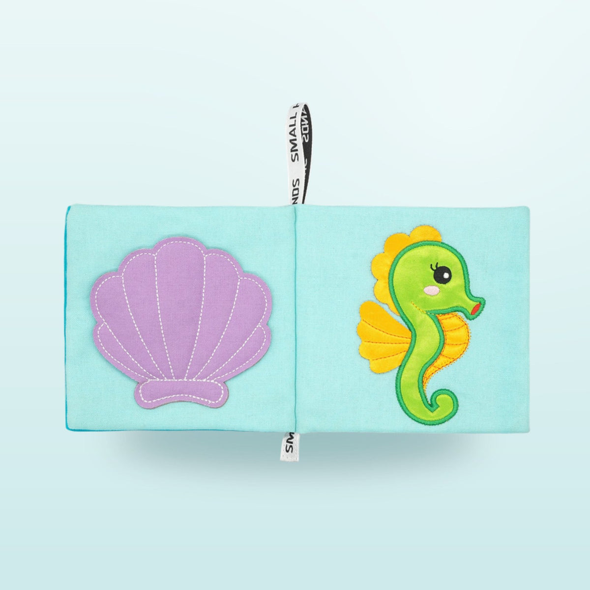 Small Hands Sea Animals Montessori cloth book double page with shell and seahorse on a soft underwater blue background – from 1 year