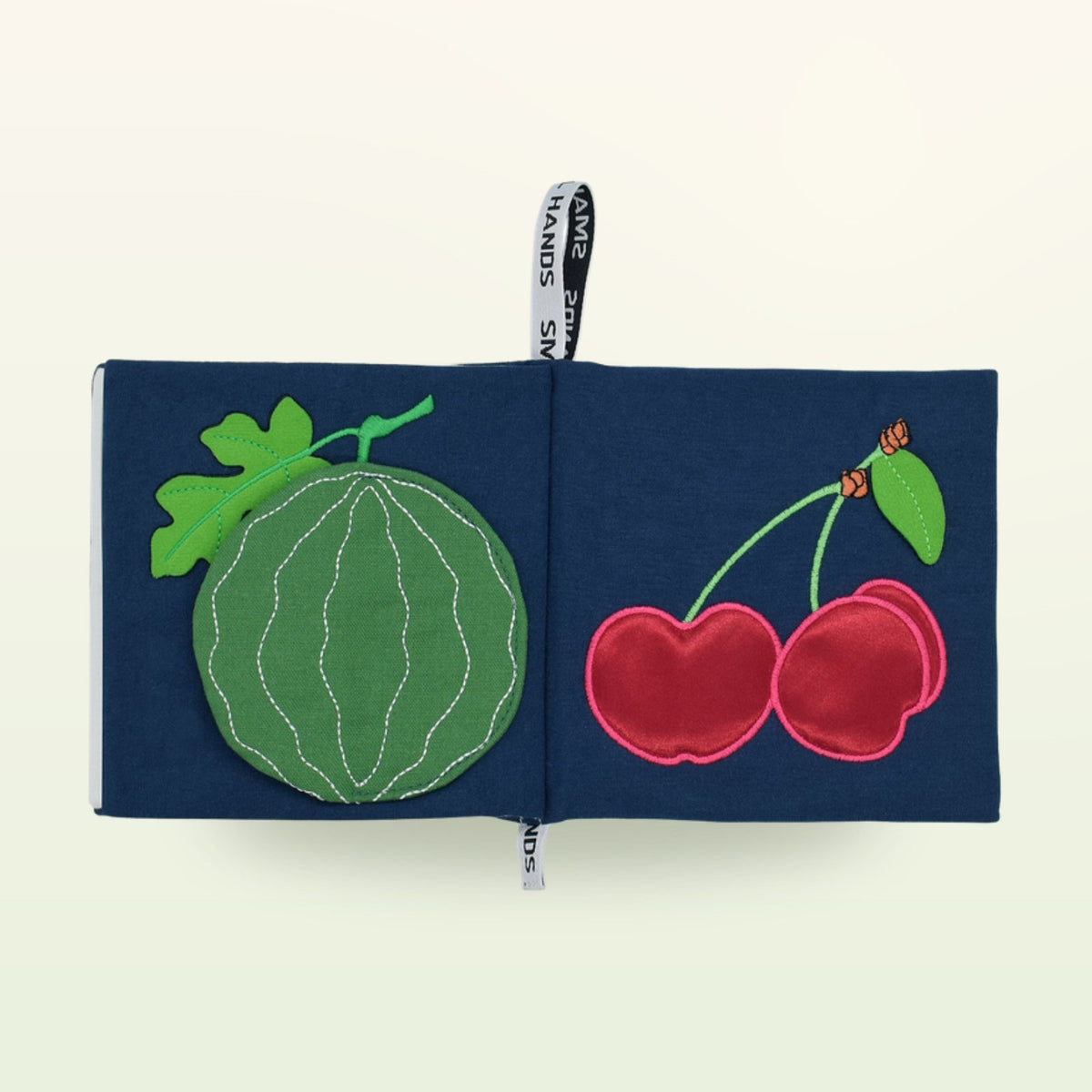 Small Hands Exotic Fruits Montessori cloth book open – watermelon and cherries on a soft cream background – from 0 months