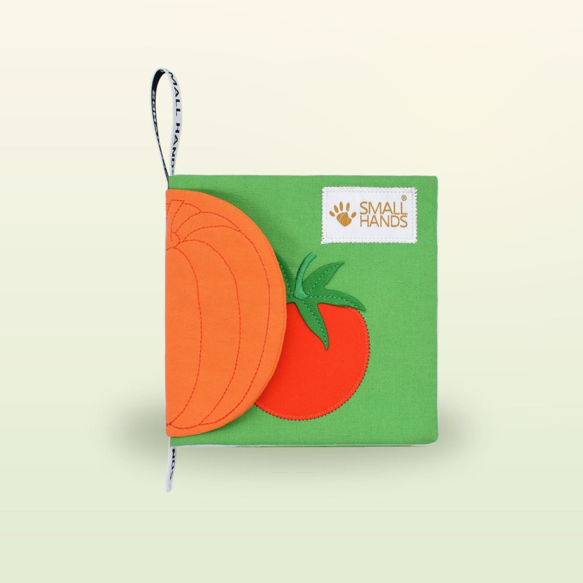 Small Hands Vegetables Montessori cloth book cover at an angle on a soft meadow green background – from 1 year