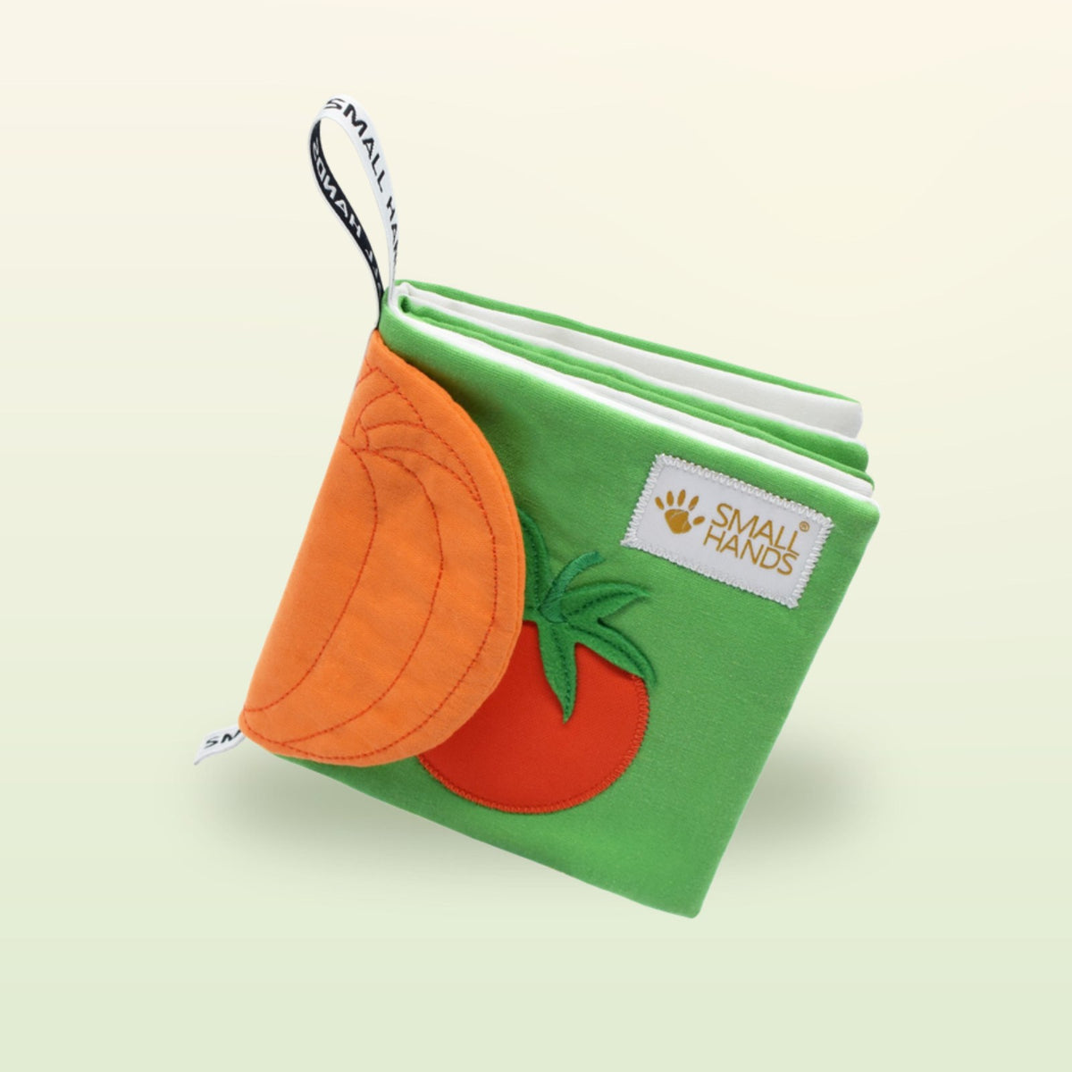 Small Hands Vegetables Montessori cloth book standing with hanging loop on a soft meadow green background – from 1 year