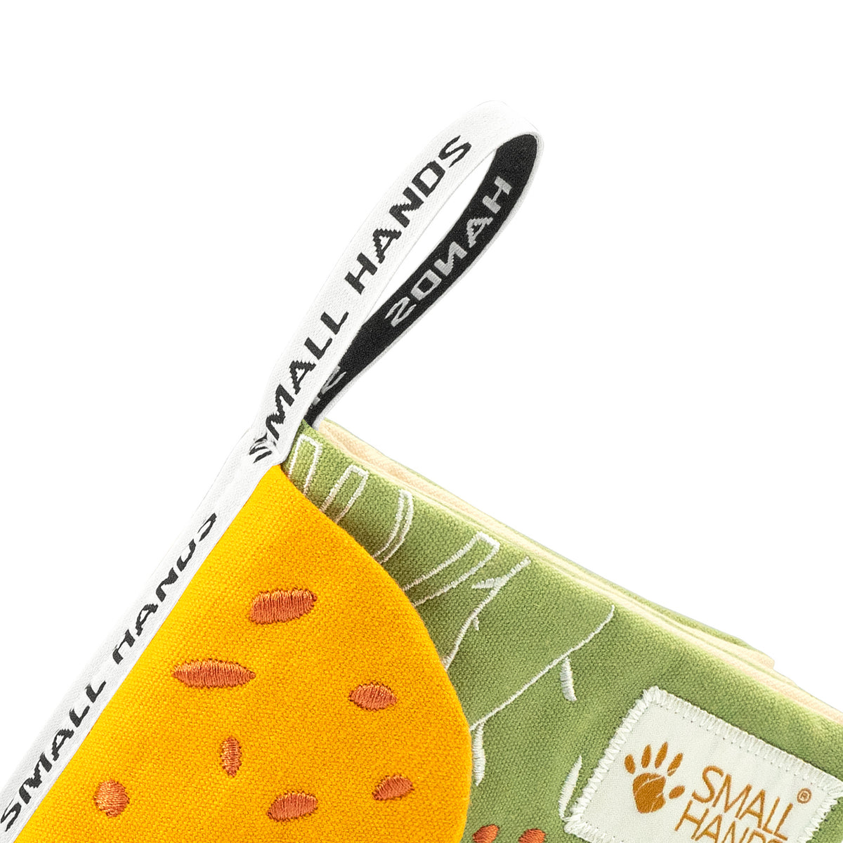 Animals of Africa Montessori sensory cloth book – close-up of the white hanging loop with Small Hands lettering on the book corner, above the yellow giraffe with orange spots, for babies