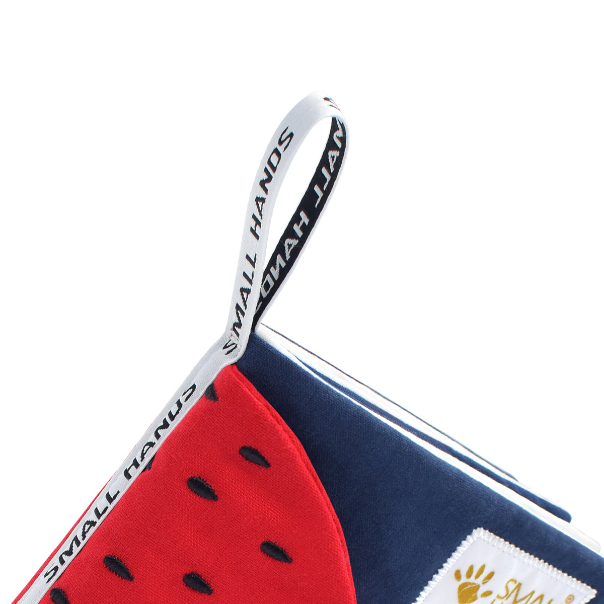 Colorful Fruits Montessori sensory cloth book – close-up of the white hanging loop with Small Hands lettering on the navy blue book corner, above the red strawberry, for babies