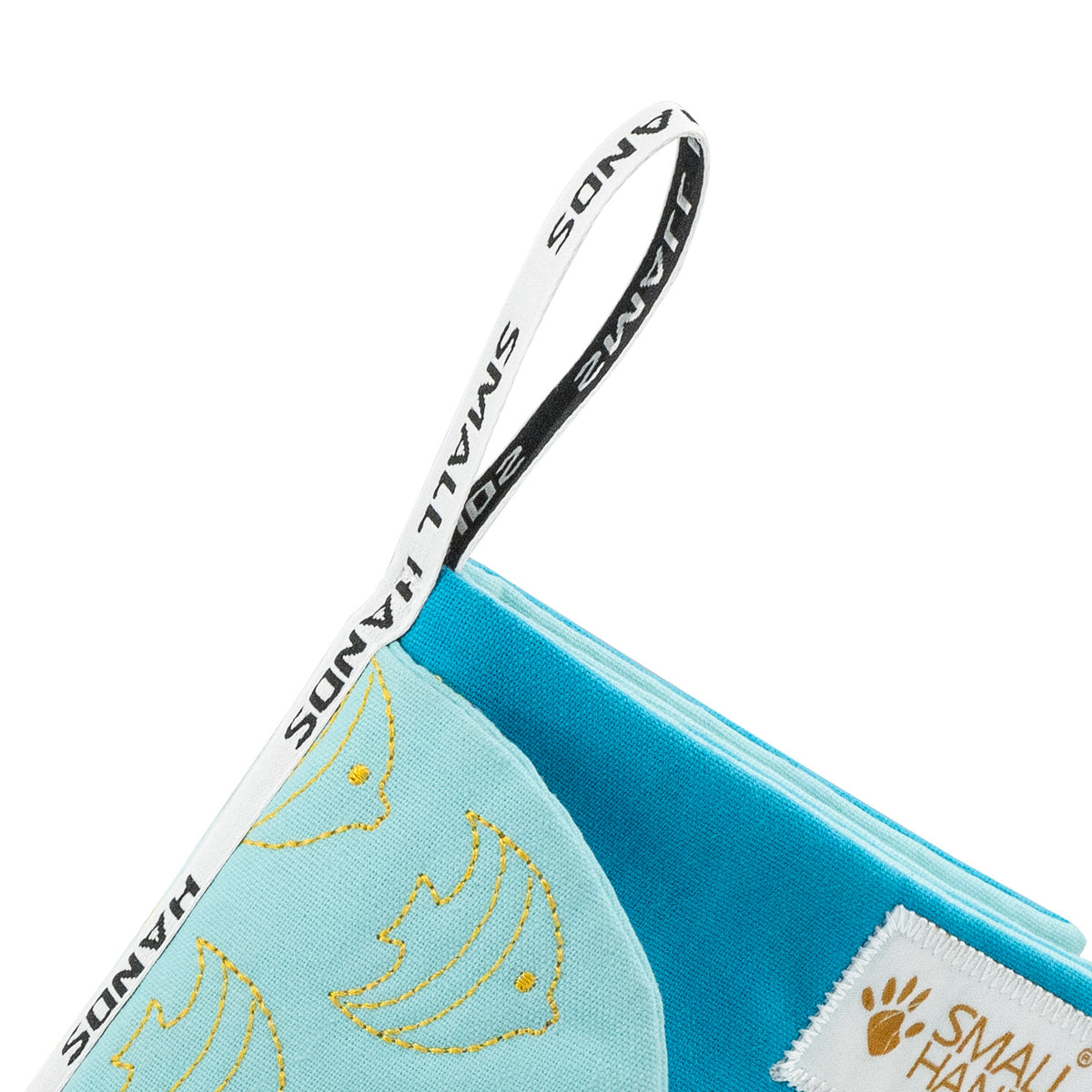 Sea Animals Montessori sensory cloth book by Small Hands – close-up of the printed SMALL HANDS fabric hanging loop on the turquoise corner with embroidered fish